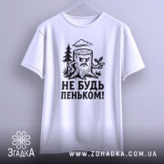 Футболка не будь пеньком. Біла футболка з чорним принтом, на якому зображений пеньок з гілочкою. Футболка підвішена на вішалці, фон однотонний, що підкреслює простоту дизайну.