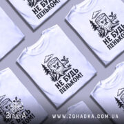 Футболка не будь пеньком. Біла футболка з чорним принтом, на якому зображений злий пеньок з гілочкою. Фон нейтральний, з легким градієнтом, що підкреслює деталі принта.