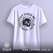 Футболка не чіпай мене. Біла футболка з принтом чорного черепа з рогами, підвішена на вішалці, фон світло-сірий, принт з написом 'DON'T TOUCH ME UNLESS I SAY SO' оточений рослинними мотивами.
