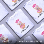 Футболка не чіпайте пузіко. Біла футболка з коротким рукавом, зображення ведмедика у купальнику з пончиком, на фоні світло-сірого градієнту. Принт яскравий, ведмедик тримає пончик, зверху напис "Не чіпайте моє пузіко...".