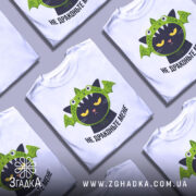 Футболка не драконьте мене, біла, зображена на манекені, фон світлий, принт з чорним котом у зеленій драконячій шапці з деталями, що нагадують драконячі крила.