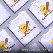 Футболка не дратуйте пташку, біла, зображена на манекені, фон світло-сірий, принт з жовтим каченям, яке тримає биту, текст червоним шрифтом.