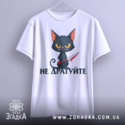 Футболка не дратуйте, білого кольору, підвішена на вішалці, фон світло-сірий, принт з чорним котом з червоним ножем, текст під котом чорного кольору, видно округлі краї рукавів.