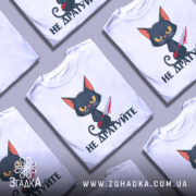 Футболка не дратуйте, білого кольору, зображена на манекені з правого боку, фон світло-сірий, принт з чорним котом з червоним ножем, текст під котом чорного кольору.