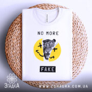 Футболка не фейк. Біла футболка, складена на плетеному кошику, з принтом тигра на жовтому фоні, текстом 'NO MORE FAKE' над принтом і чорним написом 'FAKE' внизу. Фон світло-сірий, кошик має натуральний колір.