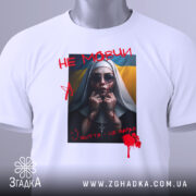 Футболка не мовчи подарунок, біла, зображена на манекені, фон світло-сірий, принт з зображенням жінки в чорному одязі з червоними плямами, написом 'НЕ МОВЧИ' і українським прапором на фоні.