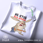 Футболка не стій над душею, біла, складена на поверхні, фон світло-сірий, принт з кроликом з сокирою, текст чорного та червоного кольору, на футболці є етикетка з зеленим шнурком.