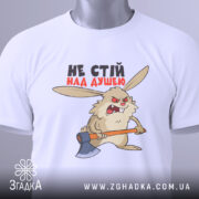 Футболка не стій над душею, біла, складена на поверхні, фон світло-сірий, принт з кроликом з сокирою, текст чорного та червоного кольору, на футболці є етикетка з зеленим шнурком.