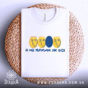 Футболка не такий як всі, біла, зображена на плетеній основі, фон світло-сірий, принт з жовтими обличчями та синім овалом, текст "Я НЕ ТАКИЙ ЯК ВСІ".