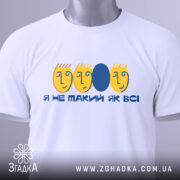 Футболка не такий як всі, біла, зображена в складеному вигляді, фон світло-сірий, принт з жовтими обличчями та синім овалом, текст "Я НЕ ТАКИЙ ЯК ВСІ", з етикеткою на зеленому шнурку.