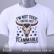 Футболка не токсичний, біла, зображена з фронтального ракурсу на манекені, фон світло-сірий, принт з черепом з рогами та текстом 'I'M NOT TOXIC YOU'RE JUST FLAMMABLE' у чорному та червоному кольорах, деталі принта чітко видимі.