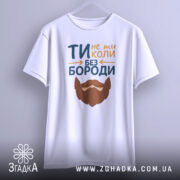 Футболка не ти без бороди. Біла футболка з коротким рукавом, підвішена на вішалці. Принт з текстом 'ТИ не ти КОЛИ БЕЗ БОРОДИ' та бородою, виконаний у яскравих кольорах. Фон світло-сірий, що створює контраст.