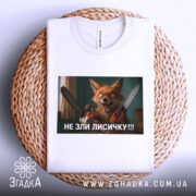 Футболка не зли лисичку. Біла футболка, складена на плетеній основі, принт з лисичкою з бензопилами, фон нейтральний, акцент на принті.