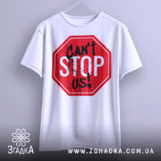 Футболка не зупинити, біла, підвішена на вішалці, фон світло-сірий, принт червоного кольору у формі знака стоп з написом 'CAN'T STOP US!' чорними буквами та краплинами фарби.