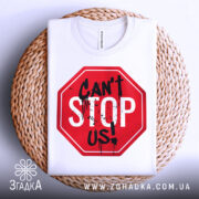Футболка не зупинити, біла, складена на плетеній кошику, фон світлий, принт червоного кольору у формі знака стоп з написом 'CAN'T STOP US!' чорними буквами та плямами фарби.