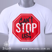 Футболка не зупинити, біла, складена на поверхні, з видимим етикеткою, фон світло-сірий, принт червоного кольору у формі знака стоп з написом 'CAN'T STOP US!' чорними буквами та плямами фарби.
