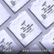 Футболка немає дрона. Біла футболка на манекені, зображена з правого ракурсу, фон світло-сірий. Принт чорного кольору з малюнком персонажа в шоломі та дрона, текст українською мовою.