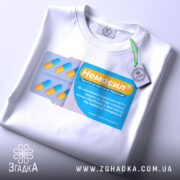 Футболка немасил терпіти, біла, складена на поверхні, фон світлий, принт з упаковкою капсул, жовті та блакитні кольори, текст на принті українською мовою, з етикеткою на рукаві.