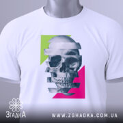 Футболка неоновий череп, біла, складена на поверхні, фон світло-сірий, принт з черепом, розділеним на смуги, з яскравими зеленими та рожевими геометричними формами, з етикеткою на зеленому шнурку.