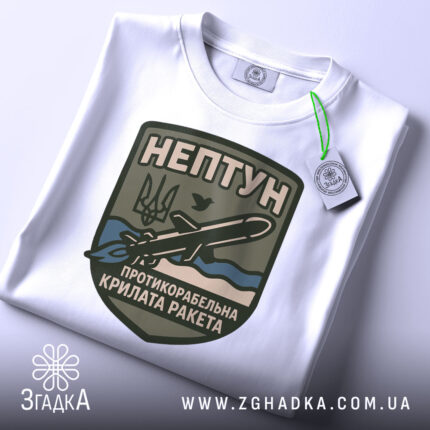 Футболка нептун крилата ракета, біла, зображена зверху, на ній прикріплений тег, фон світло-сірий, принт з зображенням ракети та текстом на темно-зеленому фоні.