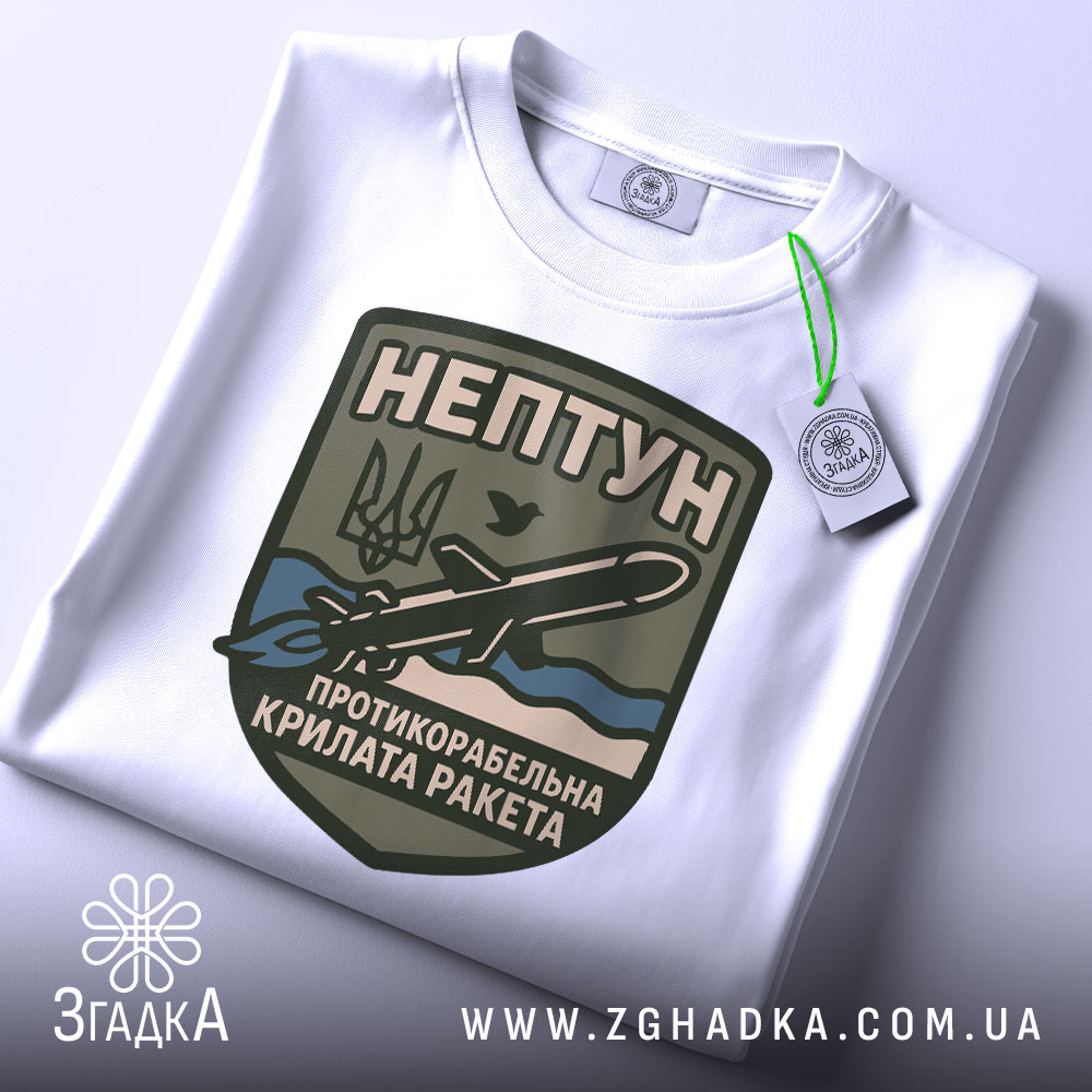 Футболка нептун крилата ракета, біла, зображена зверху, на ній прикріплений тег, фон світло-сірий, принт з зображенням ракети та текстом на темно-зеленому фоні.