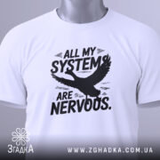 Футболка нервові системи білого кольору, складена на столі, фон світло-сірий, принт чорного кольору з написом 'ALL MY SYSTEMS ARE NERVOUS.' та зображенням орла, на комірці є етикетка.