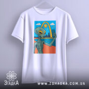 Футболка неземний вайб, біла, підвішена на вішалці, фон світло-сірий, принт з інопланетянином, що робить селфі на фоні веселки і міста.