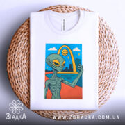 Футболка неземний вайб, біла, складена на кошику, фон світло-сірий, принт з інопланетянином, що робить селфі на фоні веселки і міста.