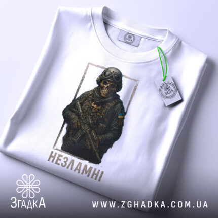 Футболка незламні воїни, біла, зображена в горизонтальному положенні, на фоні світло-сірого градієнту, принт з зображенням воїна в масці та бронежилеті, з написом 'Незламні' під ним, з етикеткою на шнурку.