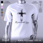 Футболка незламність духу, білого кольору, зображена на манекені з блискучою поверхнею, фон нейтральний, принт чорного кольору з зображенням хреста та написом 'Незламність духу'.