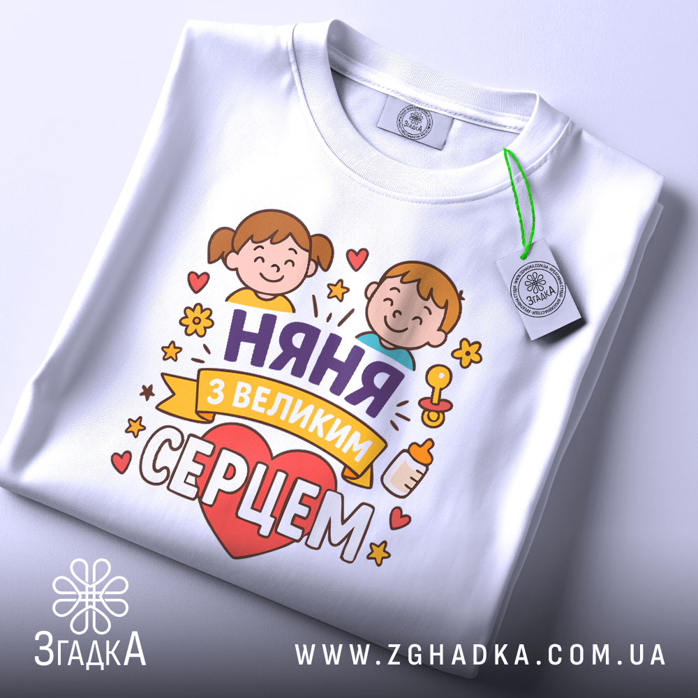 Футболка няня, білого кольору, зображена зверху, складена на поверхні, фон світло-сірий, принт з двома дітьми, серцем та написом 'няня з великим серцем', на комірці видна етикетка.