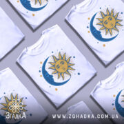 Футболка ніч і день, біла, зображена з правого боку, на фоні світло-сірого кольору, з принтом, що зображає сонце та місяць, оточені зірками, сонце жовтого кольору з деталями, а місяць синій.