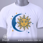 Футболка ніч і день, біла, зображена зверху, на фоні світло-сірого кольору, з принтом, що зображає сонце та місяць, з етикеткою зеленого кольору, сонце жовтого кольору з деталями, а місяць синій.