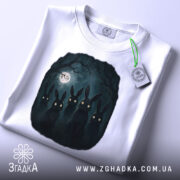 Футболка нічна таємниця, біла, складена на поверхні, фон світло-сірий, принт з п'ятьма чорними зайцями з яскравими очима, на комірці є етикетка.