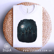 Футболка нічна таємниця, біла, складена на плетеній кошику, фон світло-сірий, принт з п'ятьма чорними зайцями з яскравими очима на темному фоні з місяцем.