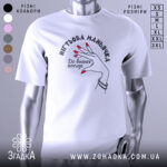 Футболка нігтьова маньячка, білого кольору, зображена з близького ракурсу на манекені, фон світло-сірий, принт з рукою з червоними нігтями та написом 'До ваших послуг'.