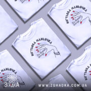 Футболка нігтьова маньячка, білого кольору, зображена з близького ракурсу на манекені, фон світло-сірий, принт з рукою з червоними нігтями та написом 'До ваших послуг'.