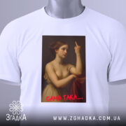 Футболка ніжність провокує, біла, зображена зверху, на фоні світлого кольору, принт з класичним зображенням жінки, що показує середній палець, з червоним написом 'САМА ТАКА....', з етикеткою зеленого кольору.