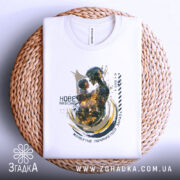 Футболка нове покоління, білого кольору, зображена зверху на плетеній основі, фон нейтральний, принт зображає роботизовану фігуру, що тримає дитину, з яскравими кольорами та абстрактними елементами.