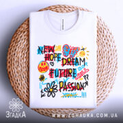 Футболка нові мрії графіті, біла, зображена зверху на плетеному кошику, фон світло-сірий, принт кольоровий з написами 'NEW HOPE DREAM FUTURE PASSION', малюнки метелика, усміхненого обличчя, сонця та квітки.