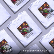 Футболка новорічний грінч білого кольору, зображена на манекені, фон світлий, принт з грінчем і собакою в новорічних шапках, текст "Щасливого Нового Року" під малюнком.