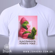 Футболка новорічний грінч, біла, зображена з верхнього ракурсу, фон світло-сірий, принт з грінчем у рожевому халаті, який жує жувальну гумку, текст "Щасливого Нового Року" під малюнком, на футболці є етикетка.