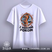 Футболка новорічний кінь, біла, підвішена на вішалці, фон світло-сірий, принт з веселим кінем, що стрибає через цегляну стіну, текст "З НОВИМ РОКОМ" під принтом.