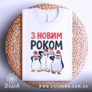 Футболка новий рік пінгвіни, біла, з верхнього ракурсу, на плетеній кошику, фон світлий, принт з чотирма пінгвінами у червоних новорічних шапках, текст 'З НОВИМ РОКОМ' у червоному та чорному кольорах.
