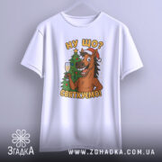 Футболка ну що святкуємо, біла, зображена з фронтального ракурсу, на фоні світлого градієнту, принт з веселим конем у червоній шапці, що тримає келих з шампанським на фоні ялинки.