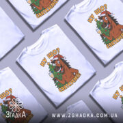 Футболка ну що святкуємо, біла, зображена з фронтального ракурсу, на фоні світлого градієнту, принт з веселим конем у червоній шапці, що тримає келих з шампанським на фоні ялинки.