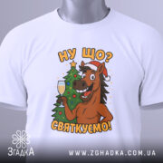 Футболка ну що святкуємо, біла, зображена зверху, на фоні світлого градієнту, принт з усміхненим конем у червоній шапці, що тримає келих з шампанським, поряд ялинка.
