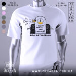 Футболка один крякає. Біла футболка на манекені, з принтом у вигляді качки, що крякає, на чорному фоні. Принт містить текст "Один крякає – інші мовчать!" та "КОД АКТИВОВАНО".