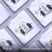 Футболка один крякає. Біла футболка на манекені, з принтом у вигляді качки, що крякає, на чорному фоні. Принт містить текст "Один крякає – інші мовчать!" та "КОД АКТИВОВАНО".