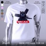 Футболка окак мем подарунок, біла футболка на манекені, з принтом чорного кота в капюшоні, на фоні з розмитим сірим кольором.